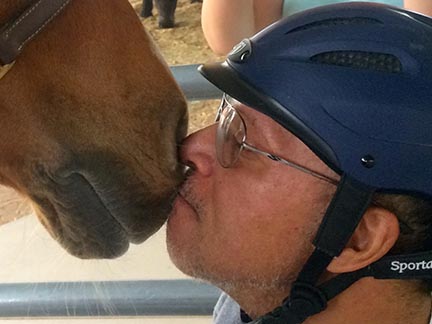helmeted man nose-to-nose with horse